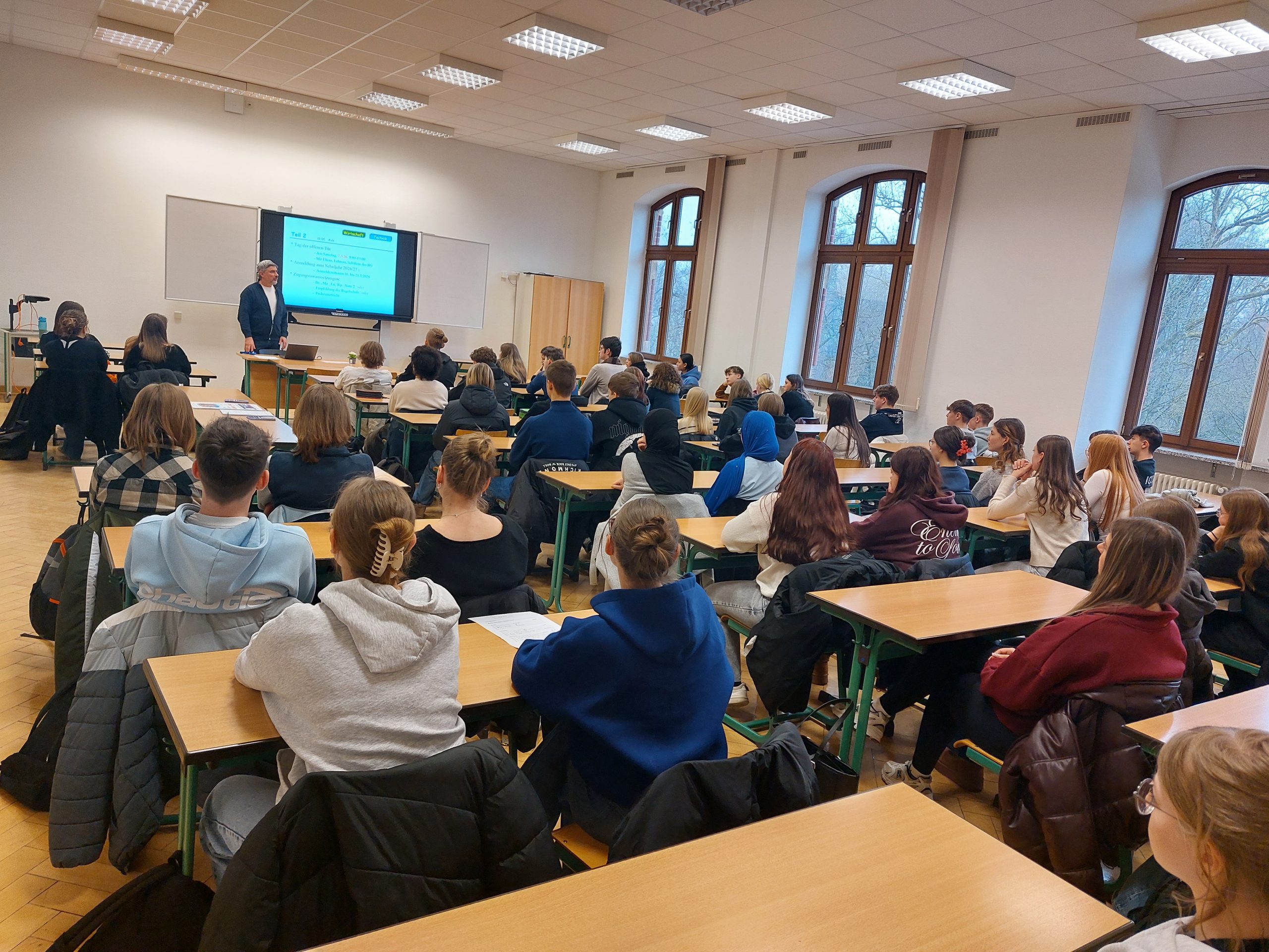 Bild aus der Aula mit den Teilnehmenden Schülern des Schnuppertags und Herrn Möller als Oberstufenleiter.